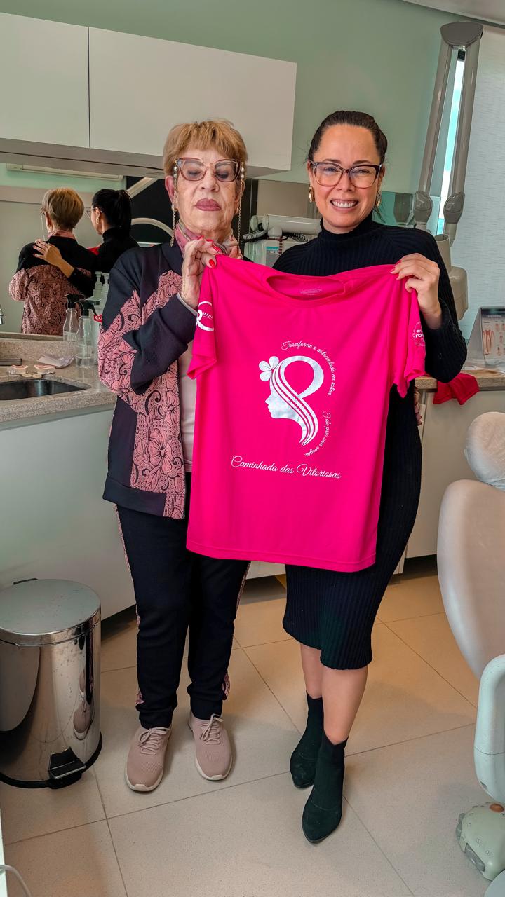 Dra. Fernanda e uma participante segurando a camiseta rosa do IMAMA