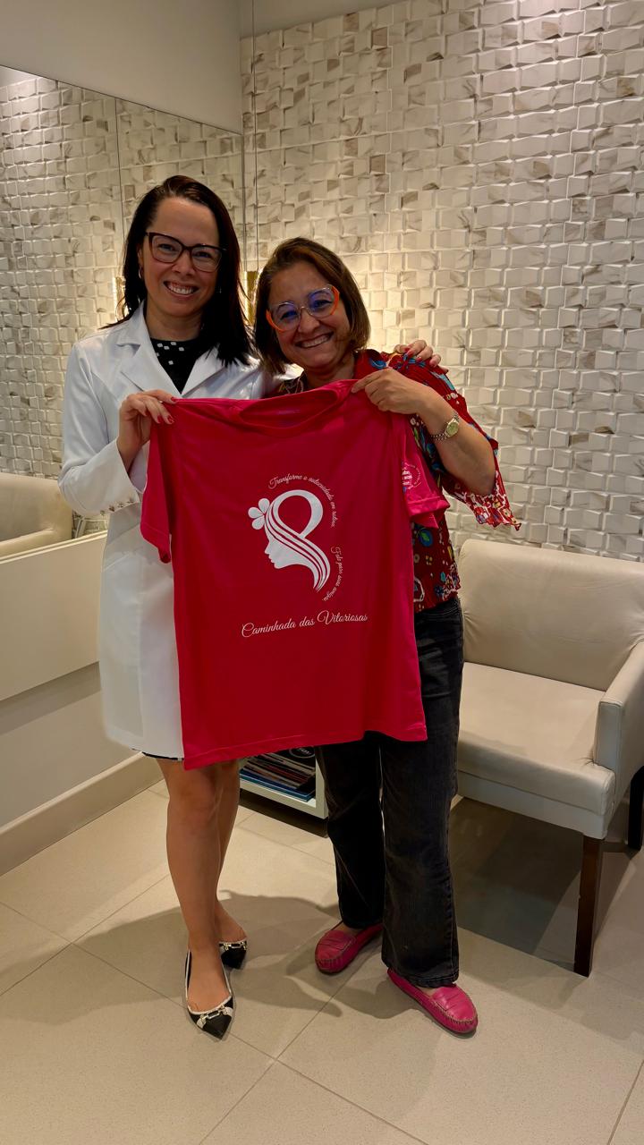 Dra. Fernanda de jaleco e participante com a camiseta do IMAMA