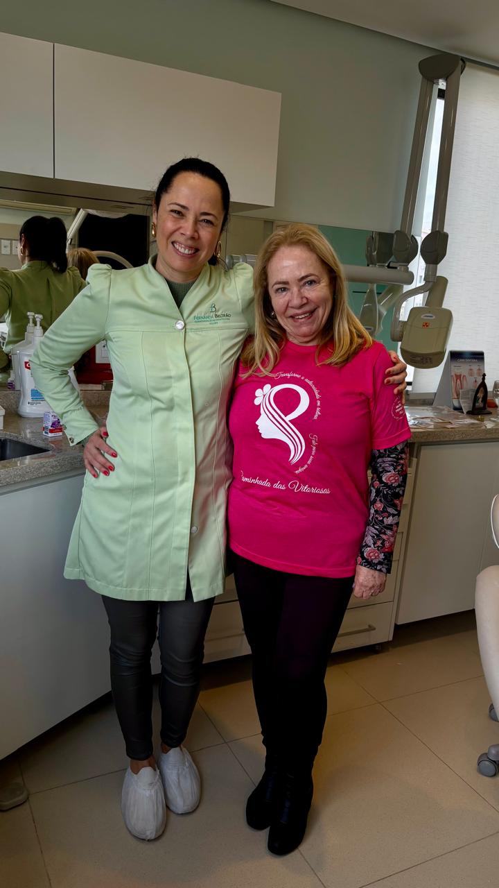 Dra. Fernanda de jaleco verde ao lado de participante com a camiseta rosa