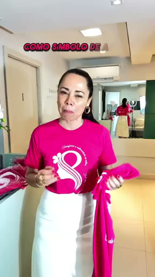 Dra. Fernanda sorrindo e vestindo a camiseta rosa